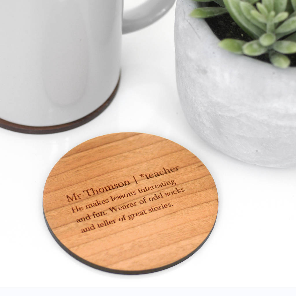 Cherry wood teacher definition coaster on a white table